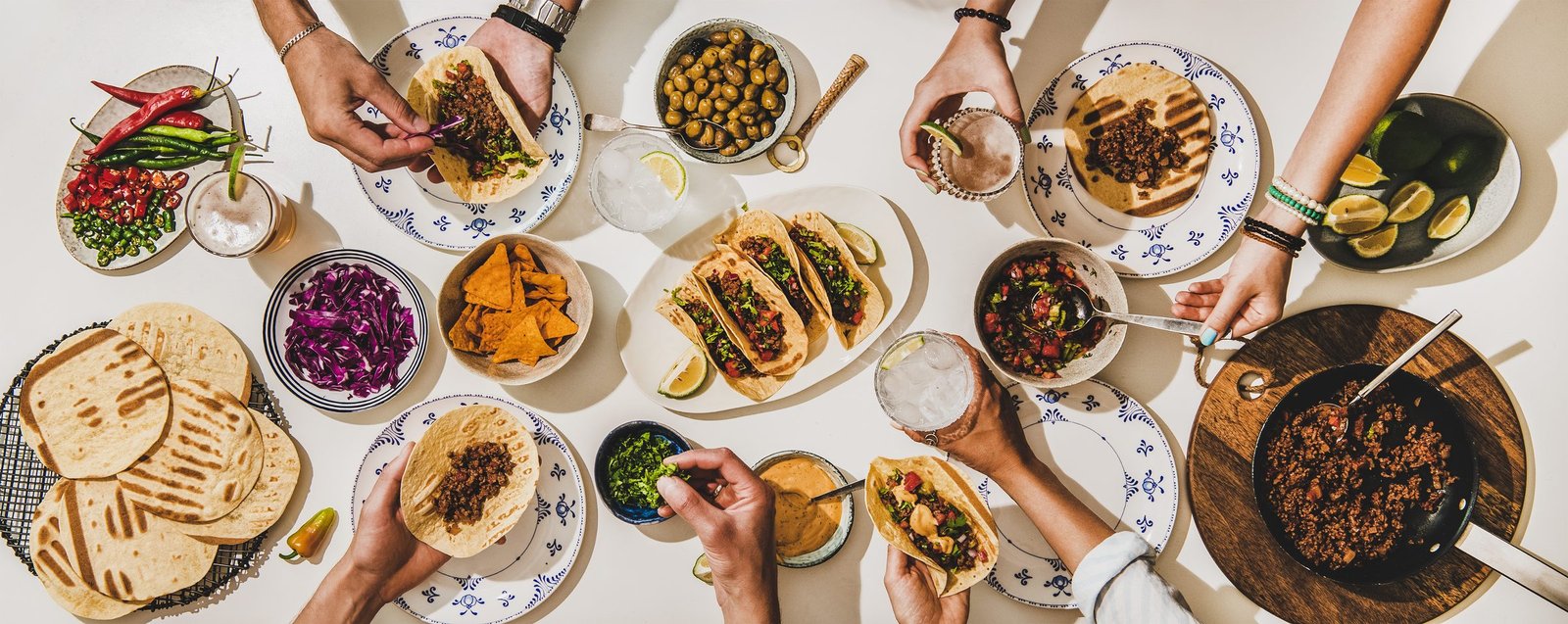 A table laid with tacos, salsas, stews and sides, seen from above